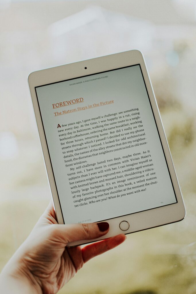 pexels-photo-3806168-3806168 Close-up of a hand holding a tablet displaying an e-book page.